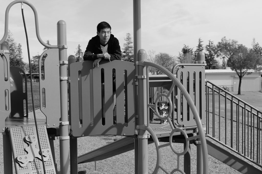 A person stands at the top of a playground, looking to the distance.